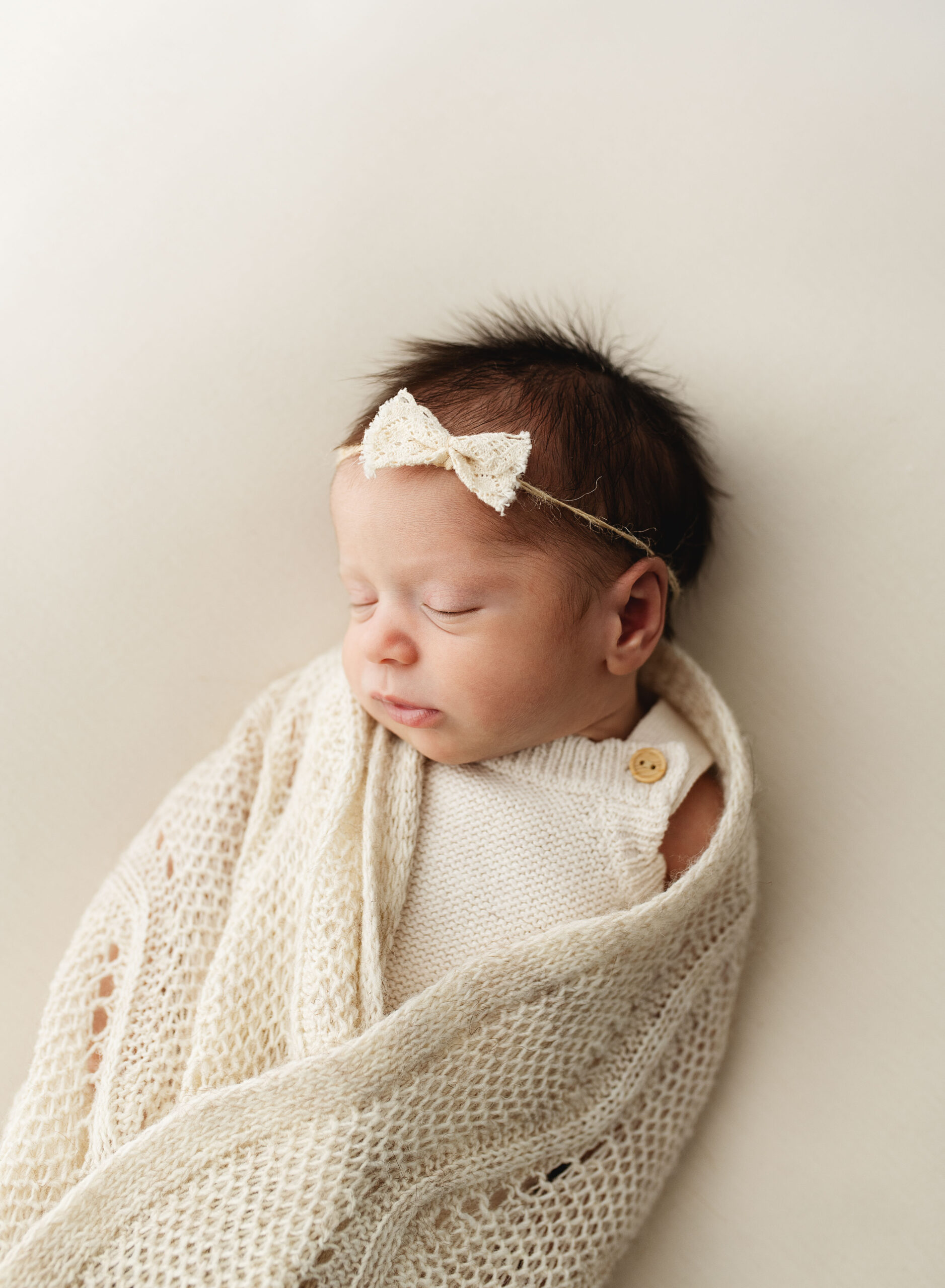 newborn baby swaddled on cream blanket during newborn photoshoot in poole, dorset.